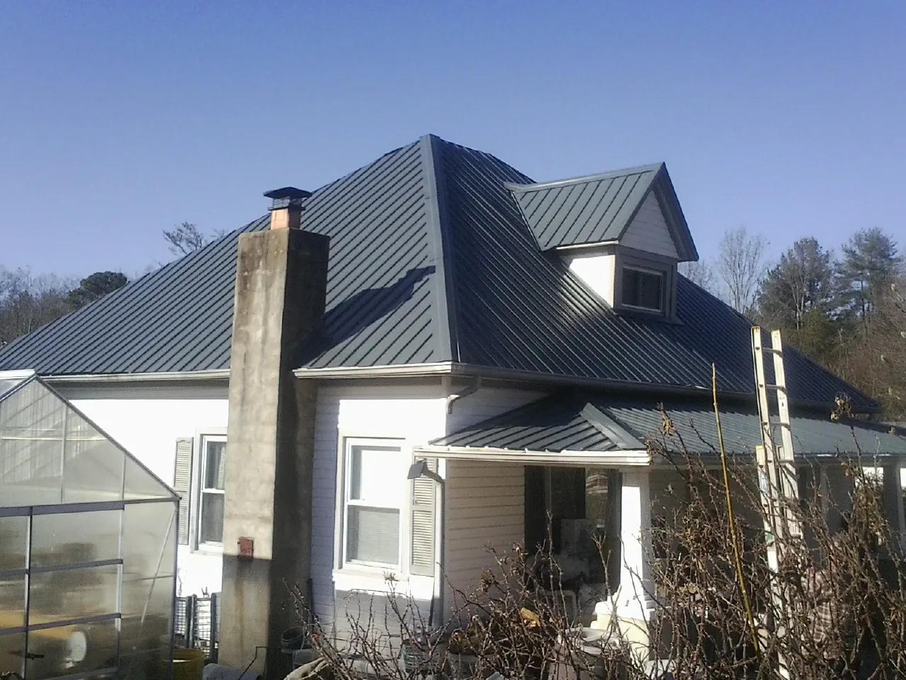 Dark blue standing seam metal roof on a white farmhouse with dormer — Slate & Tile Roof Repair by Roofing Brothers in Incline Village