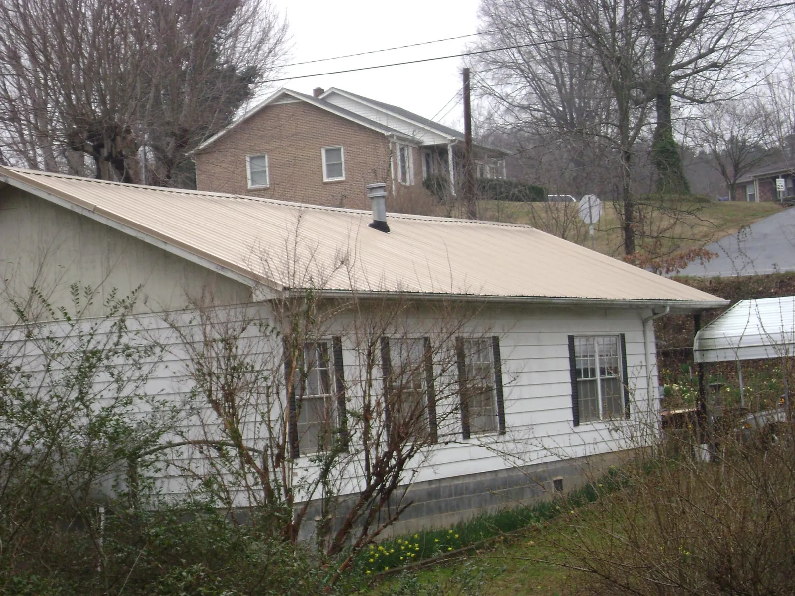 Tan metal roof on a white sided house set into a hillside — Commercial Roofing by Roofing Brothers in Incline Village