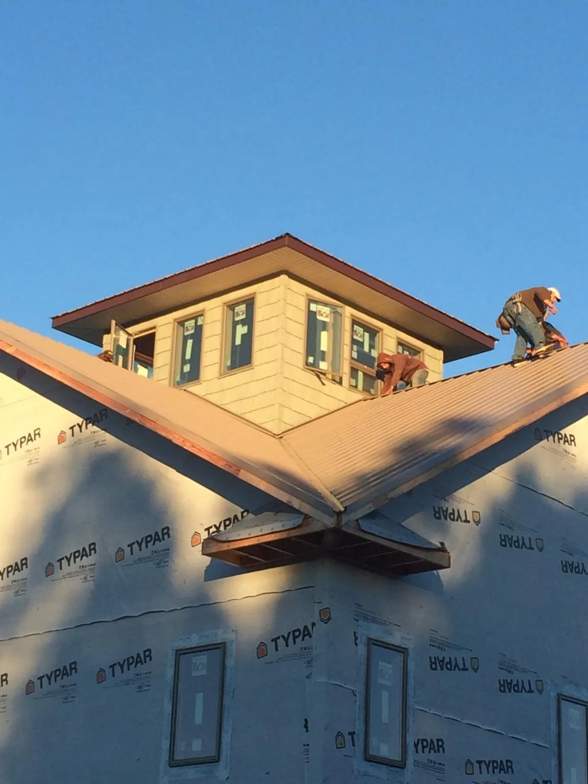 Roofers working around a rooftop cupola on a new metal roof at sunset — Roof Waterproofing in Incline Village by Roofing Brothers
